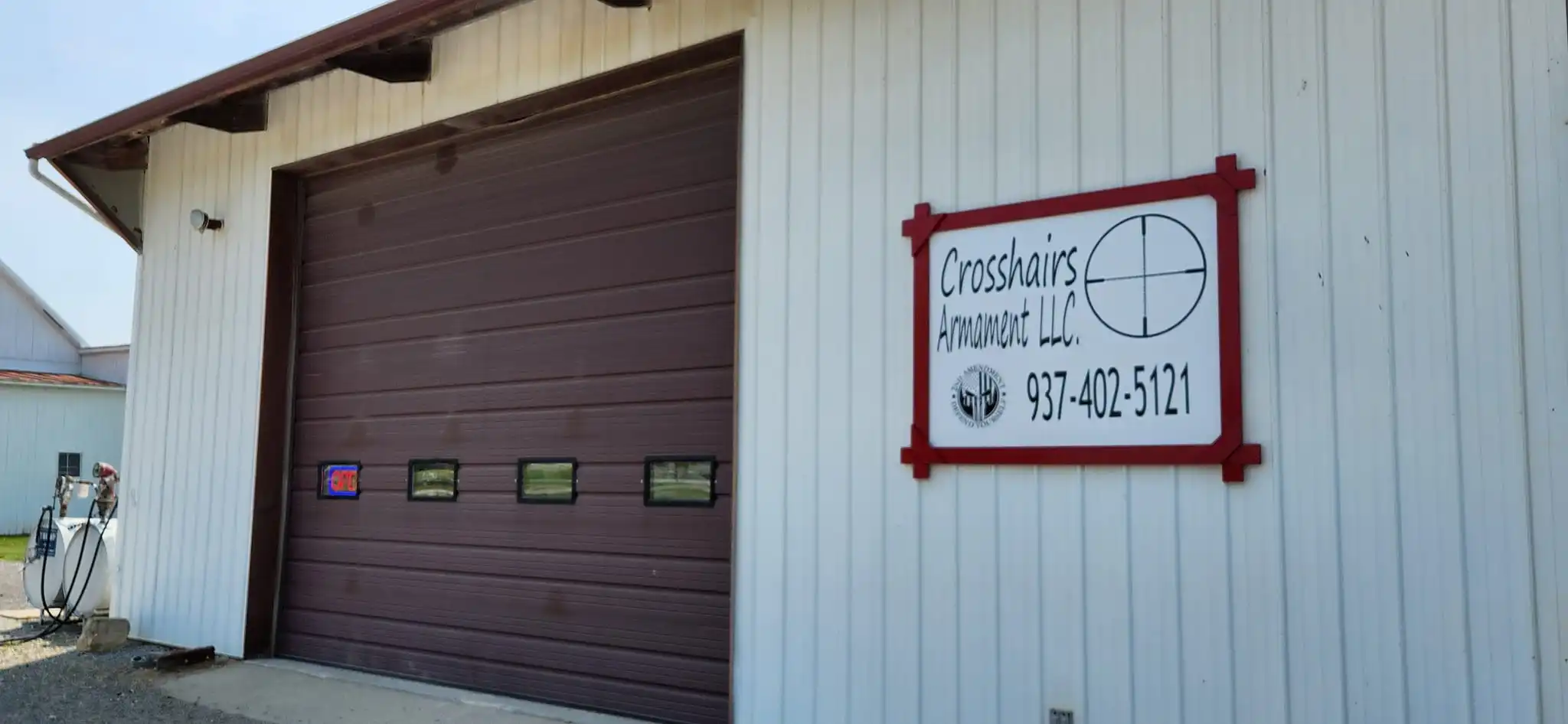 Crosshairs Armament LLC storefront with a sign displaying contact information.
